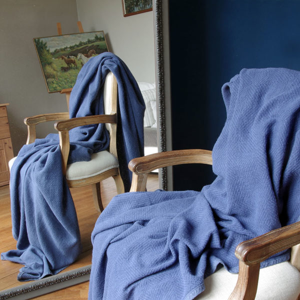 joli plaid en lin lavé couleur bleu tissage chevrons posé sur fauteuil