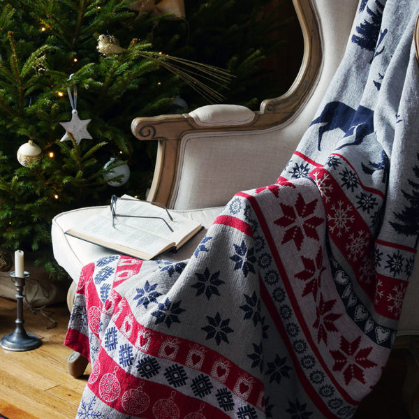 joli plaid de noël en lin lavé couleurs traditionnels style scandinave pose sur une fauteuil prés de sapin